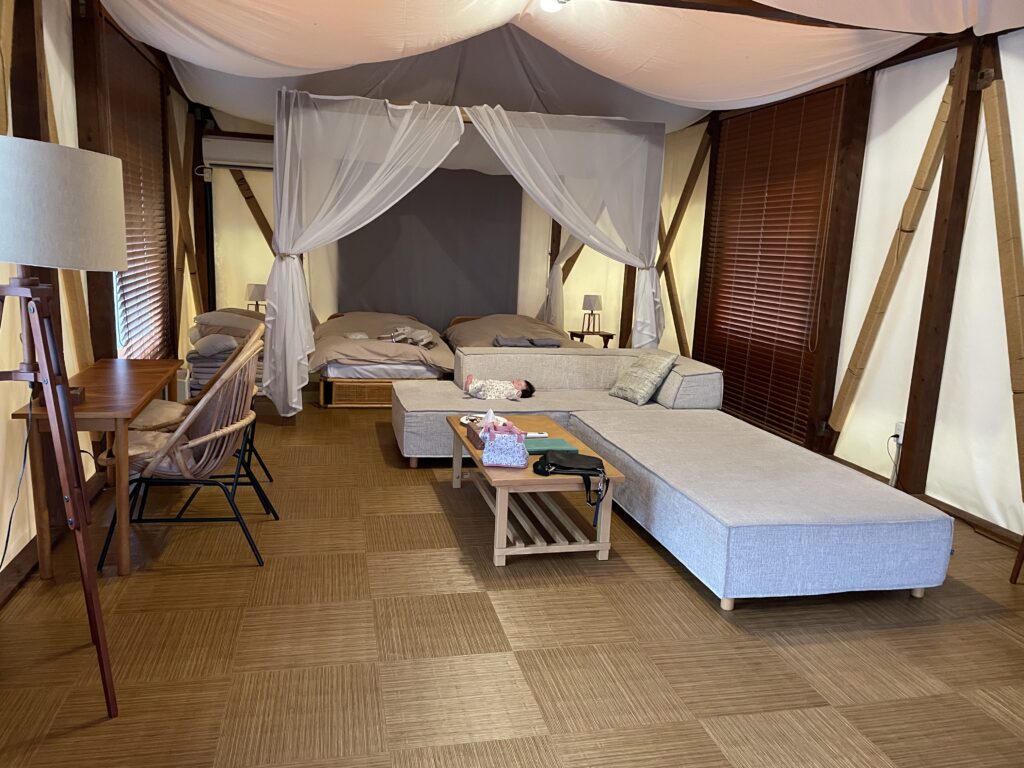 ドッグリゾートhaijmeのテラスサファリにある寝室。ベッドの上にはパジャマがあり、ベッド横には敷布団が置かれていた。